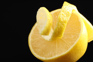 Photo of Fresh lemon peel and half of fruit on black background, closeup. Space for text