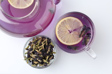 Photo of Delicious butterfly pea flower tea with lemon, teapot and dry petals on white table, flat lay