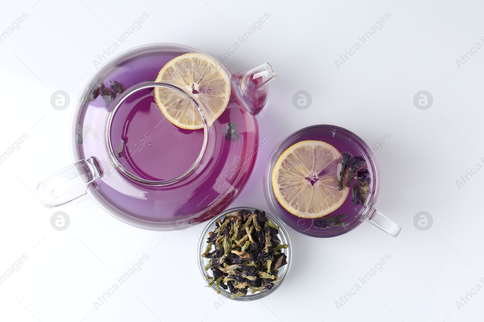 Photo of Delicious butterfly pea flower tea with lemon, teapot and dry petals on white table, flat lay