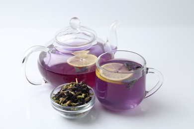 Photo of Delicious butterfly pea flower tea with lemon, teapot and dry petals on white table