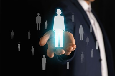 Image of Human resource. Businessman choosing one virtual figure among others on black background, closeup