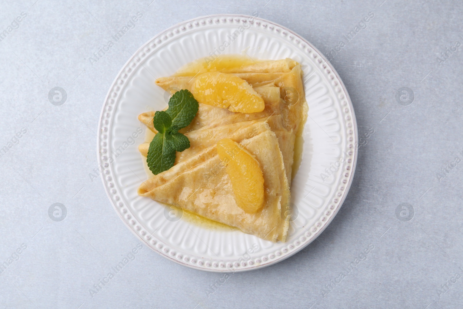 Photo of Delicious Crepes Suzette on light table, top view