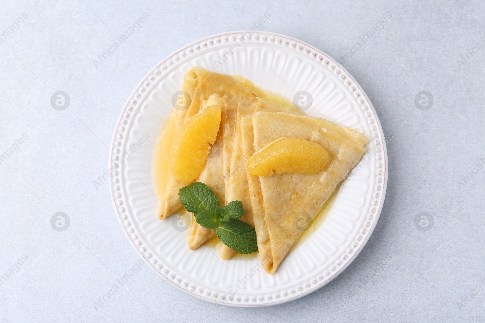 Photo of Delicious Crepes Suzette on light table, top view