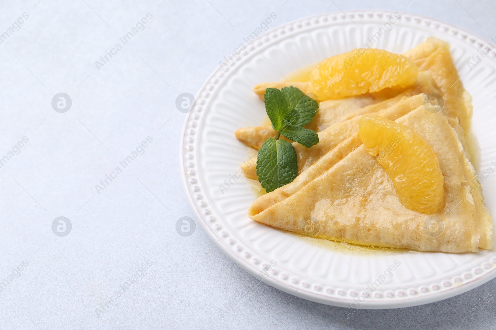 Photo of Delicious Crepes Suzette on light table, closeup. Space for text