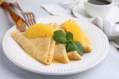 Photo of Delicious Crepes Suzette served on light table, closeup