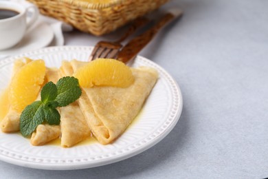 Photo of Delicious Crepes Suzette served on light table, closeup. Space for text