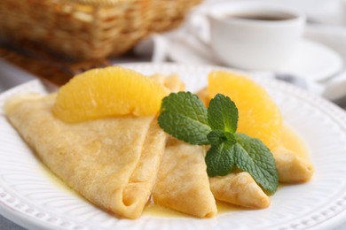 Photo of Delicious Crepes Suzette served on light table, closeup