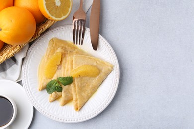 Photo of Delicious Crepes Suzette served on light table, flat lay. Space for text