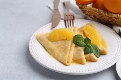 Photo of Delicious Crepes Suzette served on light table, closeup