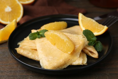 Photo of Delicious Crepes Suzette served on wooden table, closeup