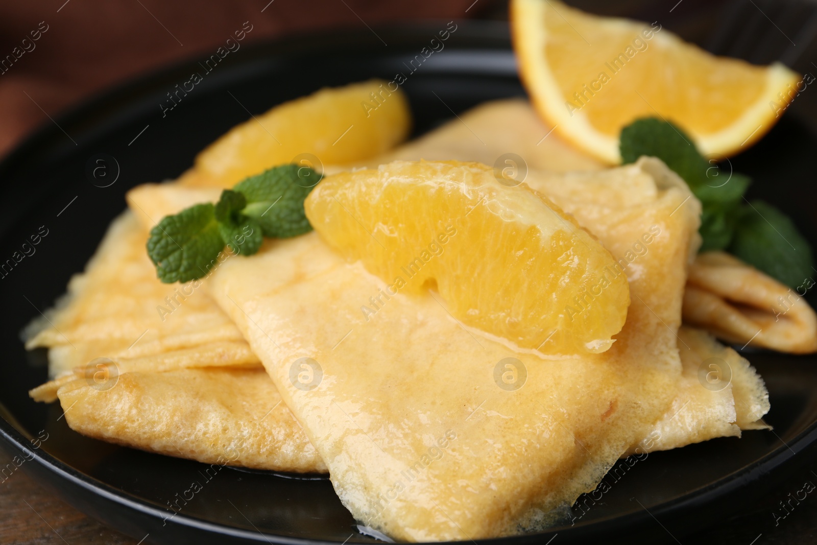 Photo of Delicious Crepes Suzette on wooden table, closeup