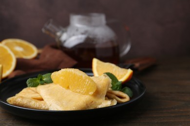 Photo of Delicious Crepes Suzette on wooden table, closeup