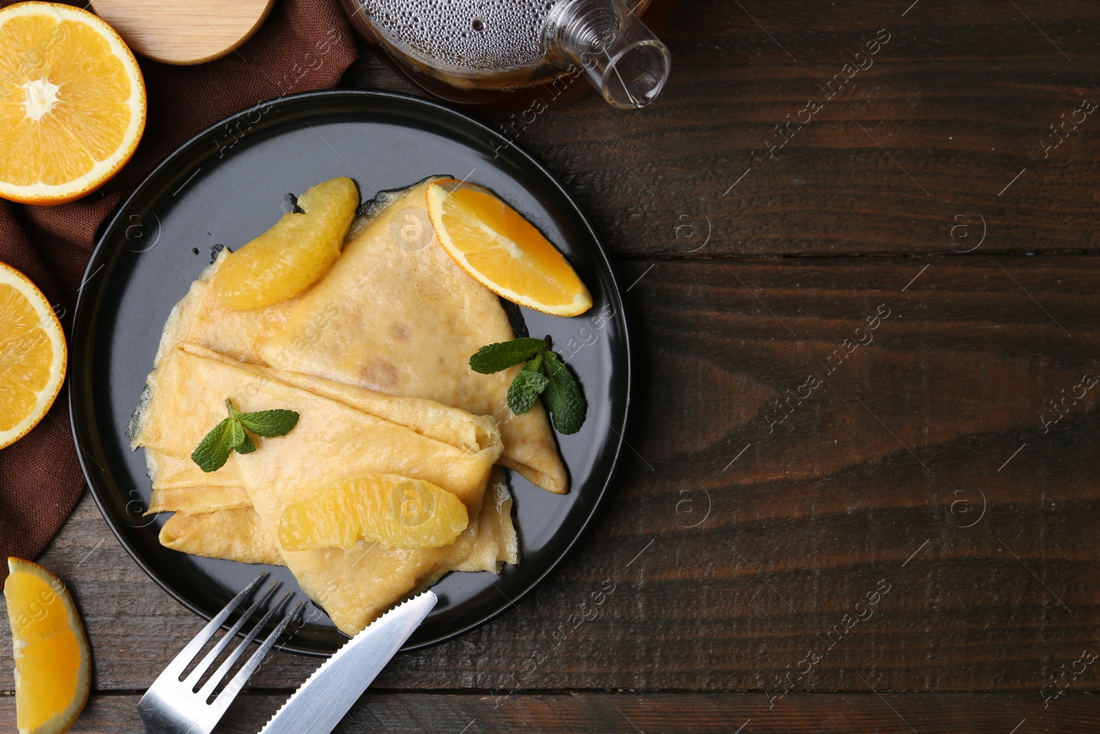 Photo of Delicious Crepes Suzette served on wooden table, flat lay. Space for text