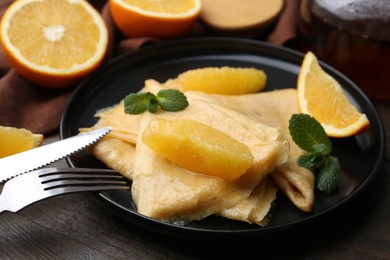 Photo of Delicious Crepes Suzette served on wooden table, closeup