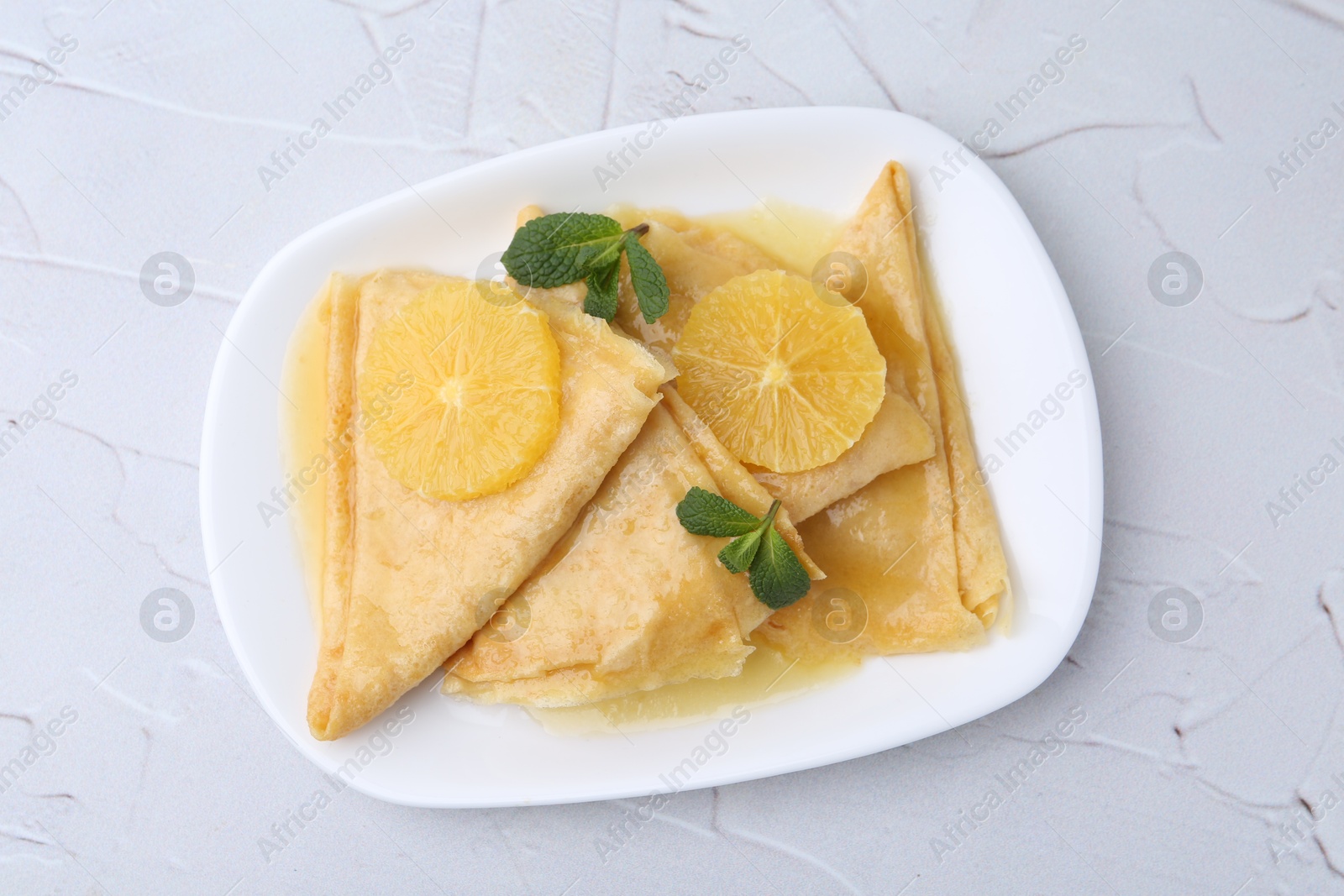 Photo of Delicious Crepes Suzette on white textured table, top view