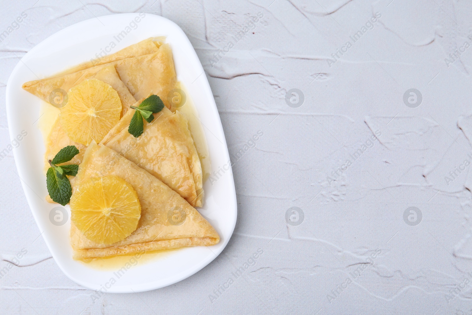 Photo of Delicious Crepes Suzette on white textured table, top view. Space for text