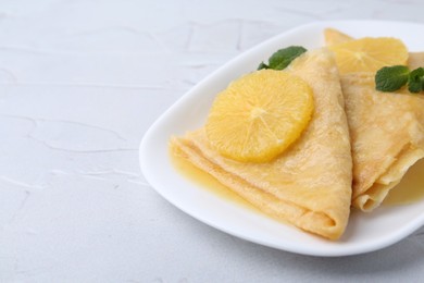 Photo of Delicious Crepes Suzette on white textured table, closeup. Space for text