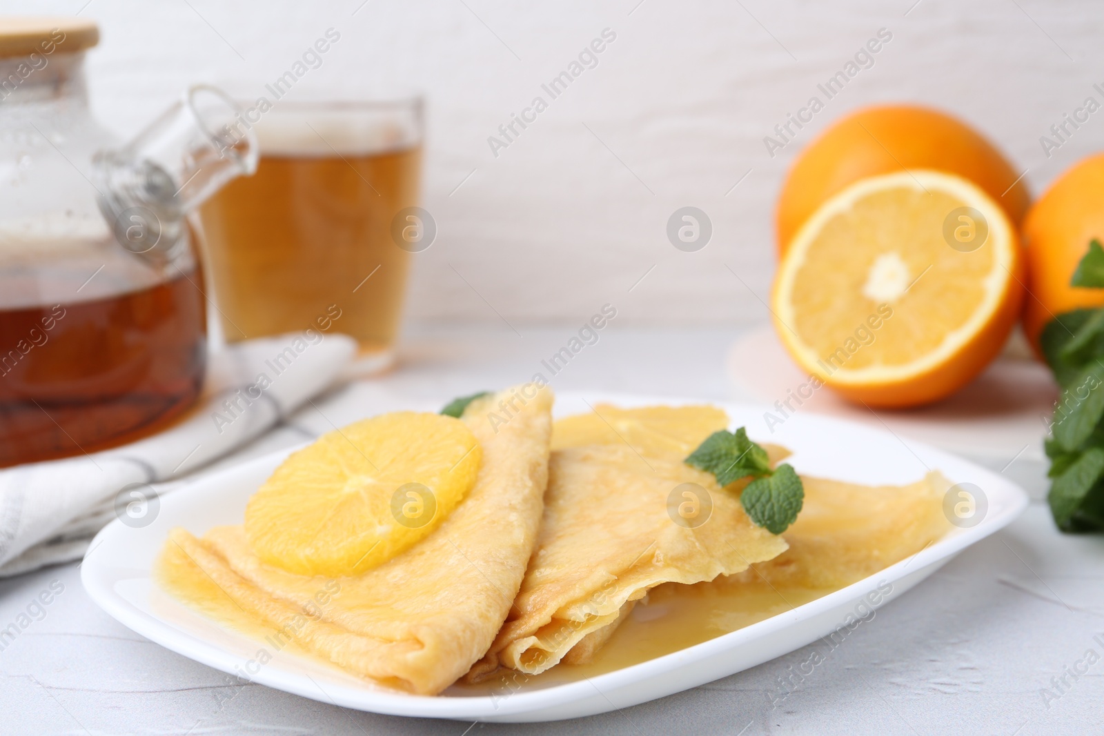 Photo of Delicious Crepes Suzette served on white textured table, closeup