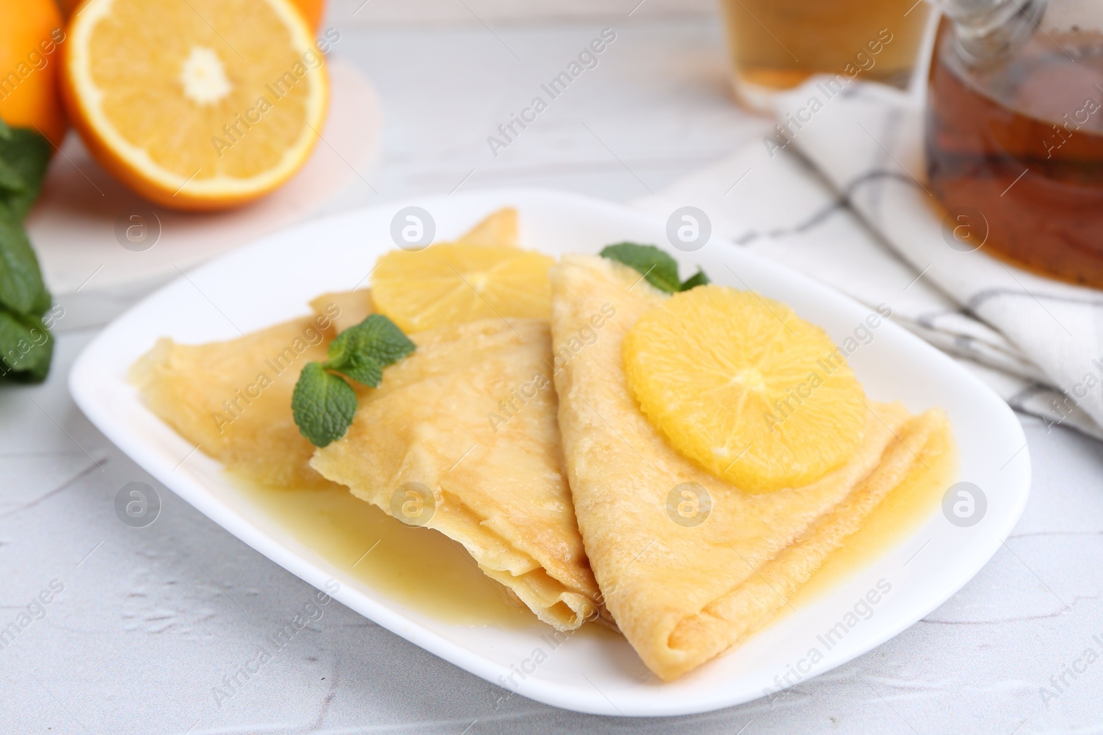 Photo of Delicious Crepes Suzette served on white textured table, closeup