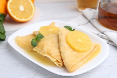 Photo of Delicious Crepes Suzette served on white textured table, closeup