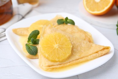 Photo of Delicious Crepes Suzette served on white textured table, closeup