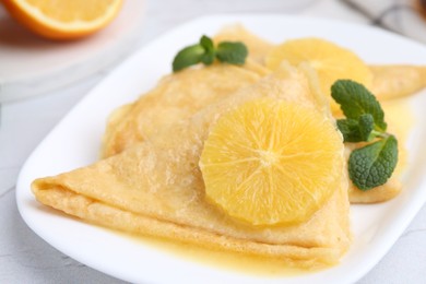 Photo of Delicious Crepes Suzette on white textured table, closeup