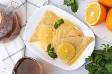 Photo of Delicious Crepes Suzette served on white textured table, flat lay