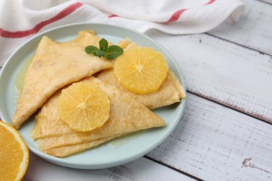 Photo of Delicious Crepes Suzette on white wooden table, closeup