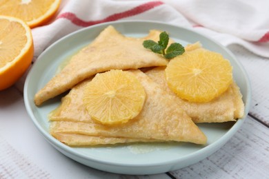 Photo of Delicious Crepes Suzette on white wooden table, closeup