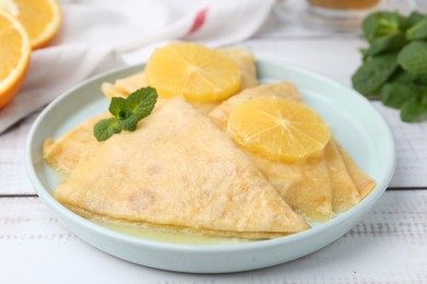 Photo of Delicious Crepes Suzette on white wooden table, closeup