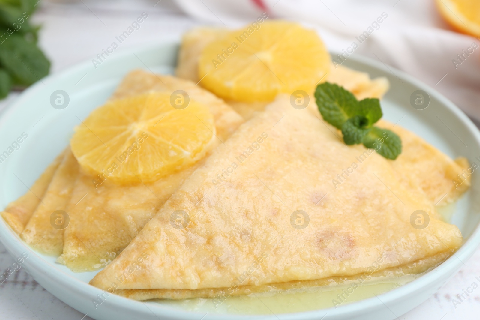 Photo of Delicious Crepes Suzette on white wooden table, closeup