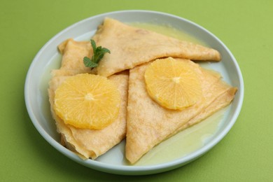 Photo of Delicious Crepes Suzette on green background, closeup