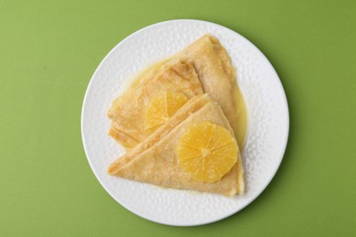 Photo of Delicious Crepes Suzette on green background, top view