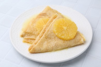 Photo of Delicious Crepes Suzette on white tiled table, closeup