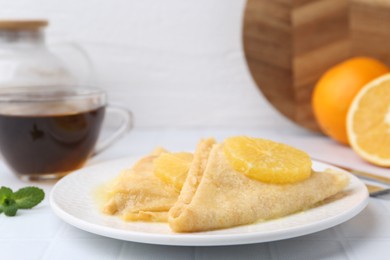 Photo of Delicious Crepes Suzette served on white tiled table, closeup