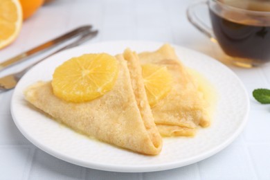 Photo of Delicious Crepes Suzette served on white tiled table, closeup