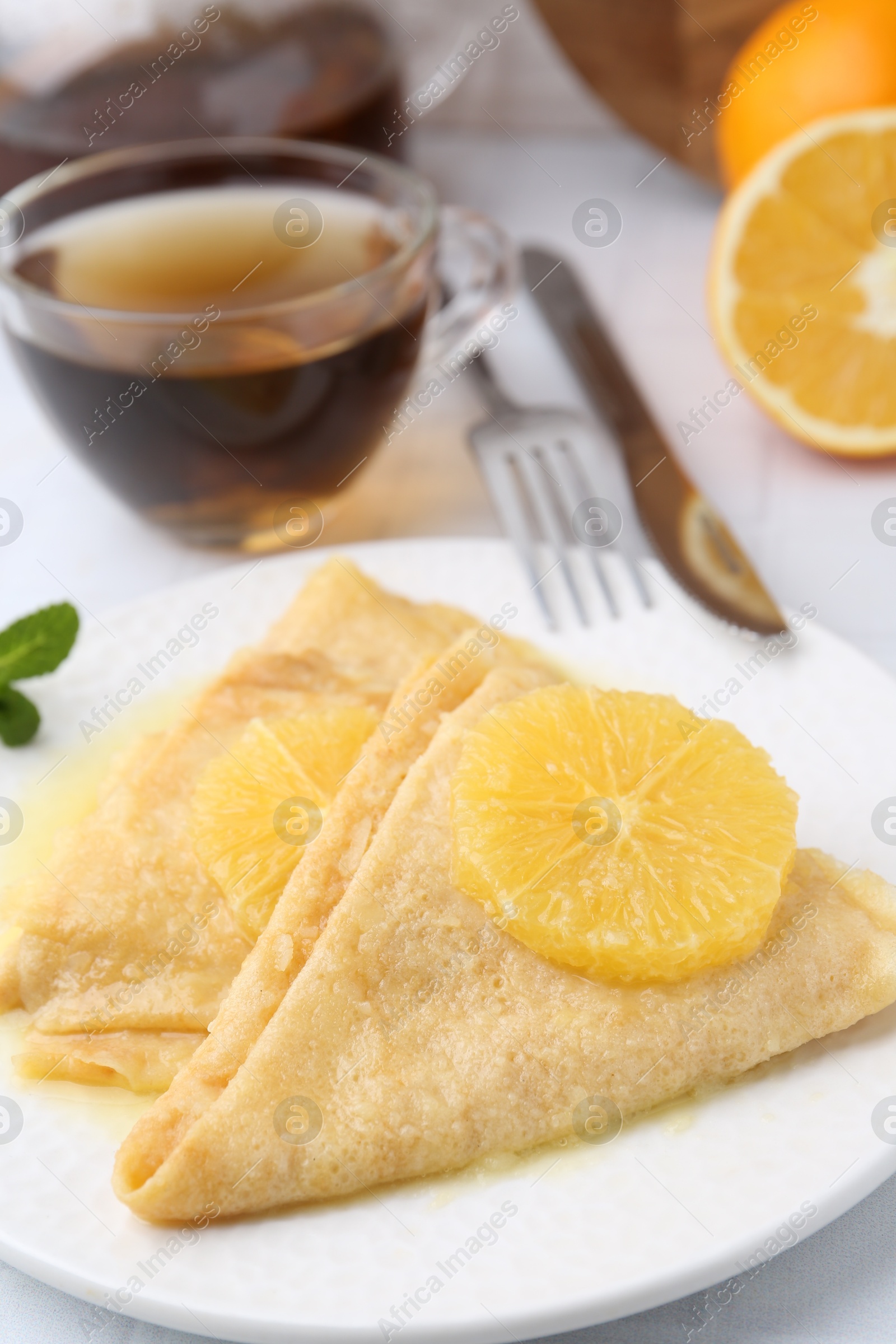 Photo of Delicious Crepes Suzette served on white tiled table, closeup