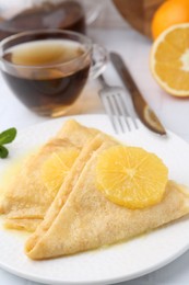 Photo of Delicious Crepes Suzette served on white tiled table, closeup