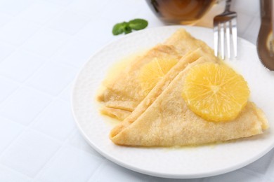 Photo of Delicious Crepes Suzette served on white tiled table, closeup. Space for text