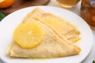 Photo of Delicious Crepes Suzette on white table, closeup