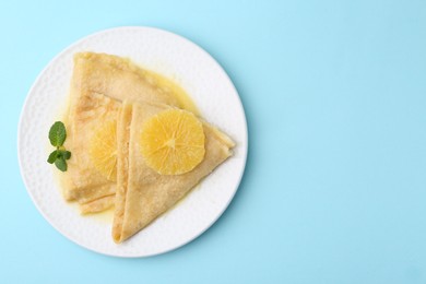 Photo of Delicious Crepes Suzette on light blue background, top view. Space for text