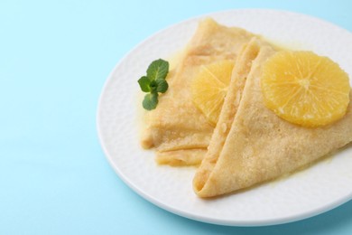 Photo of Delicious Crepes Suzette on light blue background, closeup