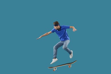 Handsome man with skateboard in air on blue background. Performing trick