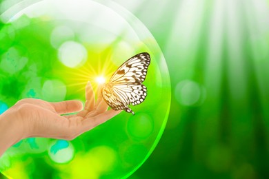 Image of Save Earth. Woman holding butterfly in sunlight outdoors, closeup. Bubble around her hand