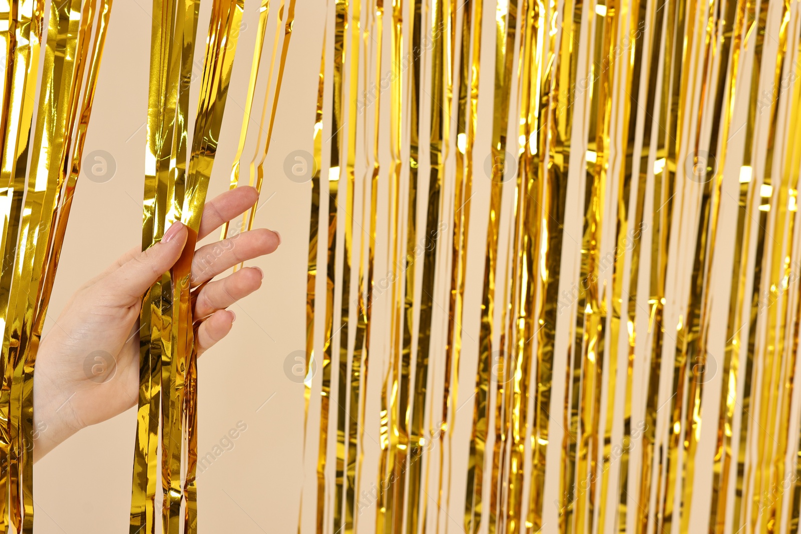 Photo of Woman near golden foil curtain against beige background, closeup