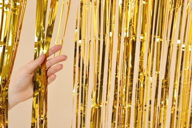 Photo of Woman near golden foil curtain against beige background, closeup