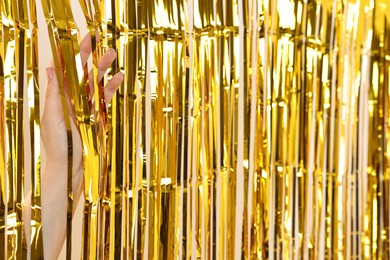 Photo of Woman near golden foil curtain against beige background, closeup