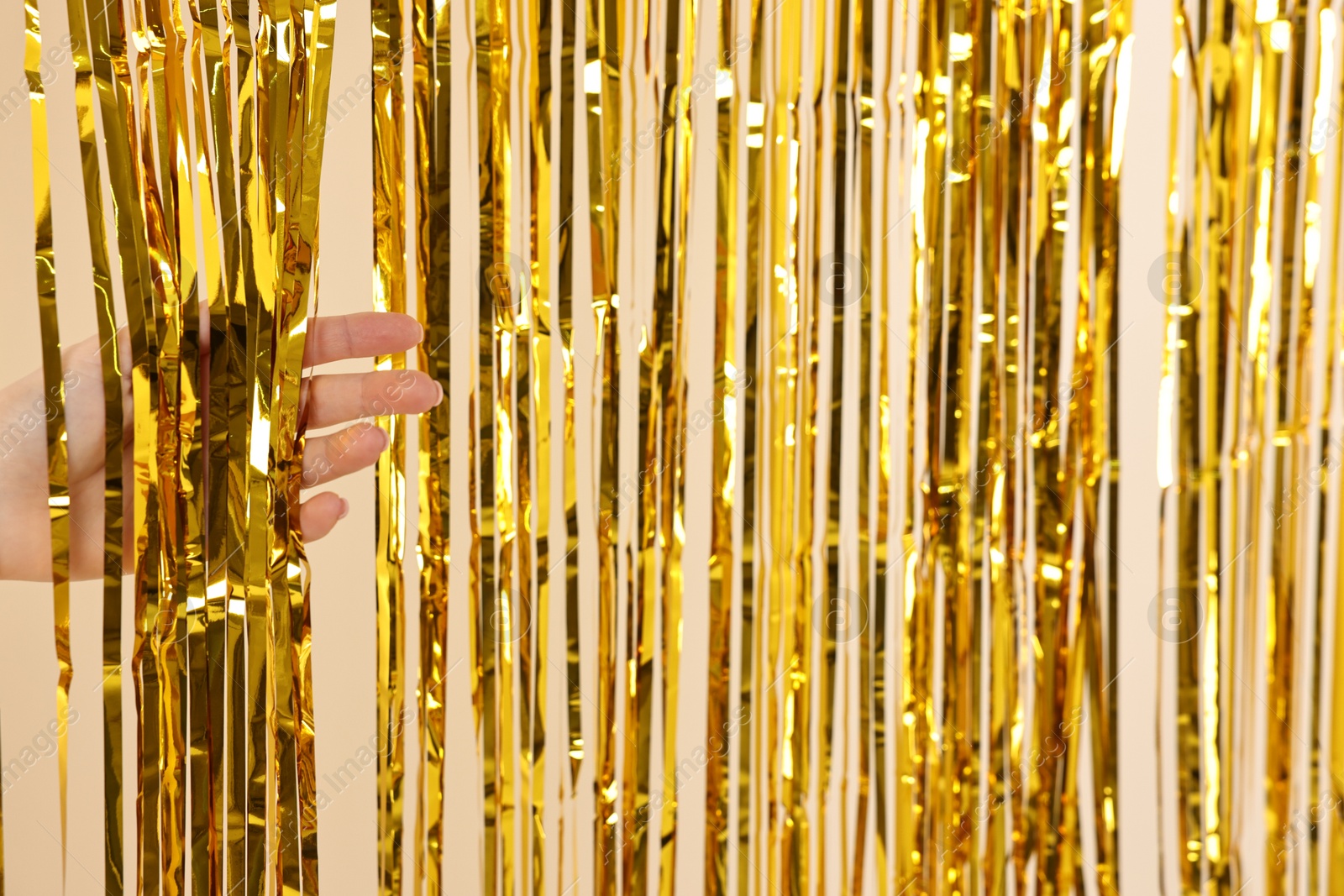 Photo of Woman near golden foil curtain against beige background, closeup