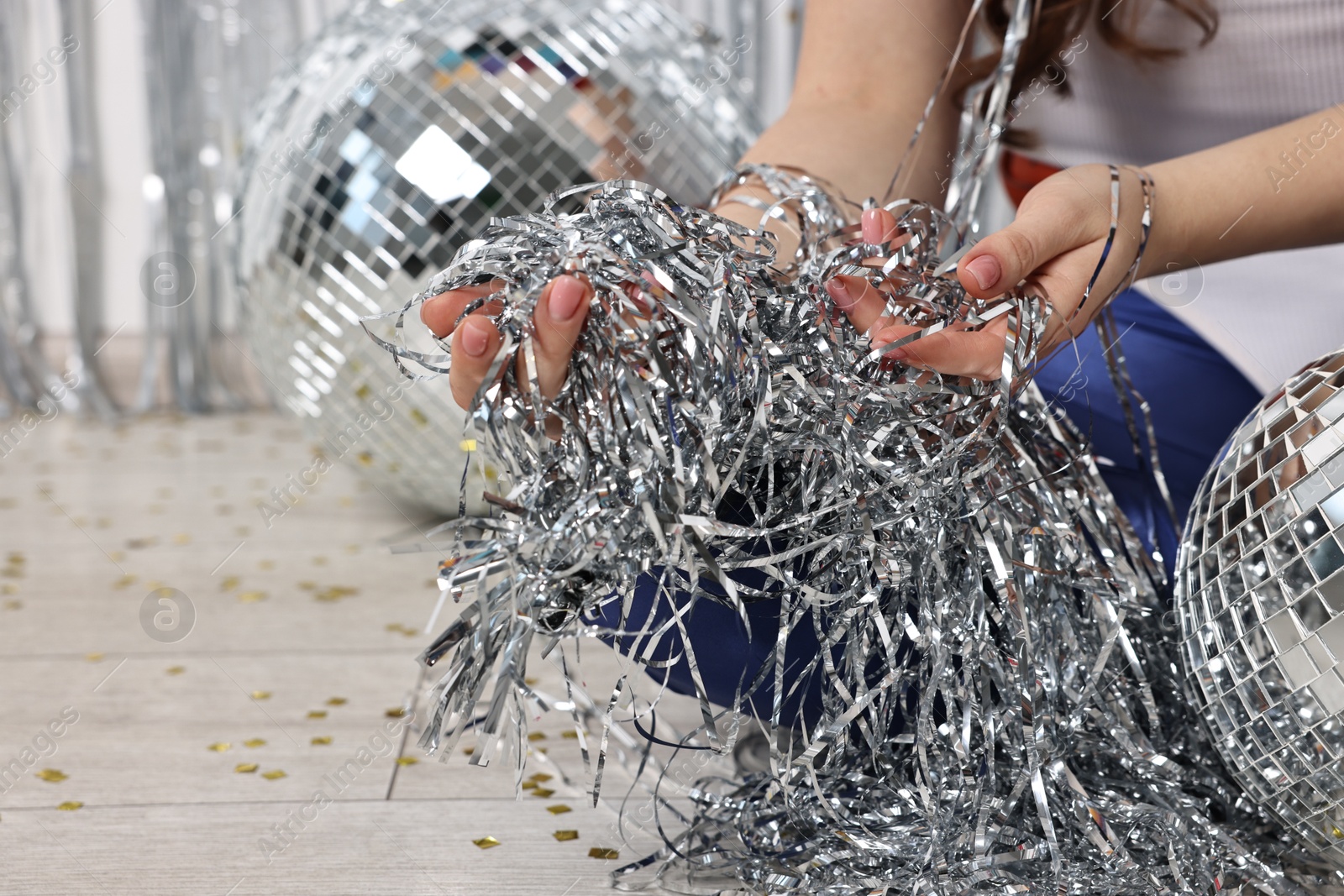 Photo of Woman with silver tinsel on floor indoors, closeup