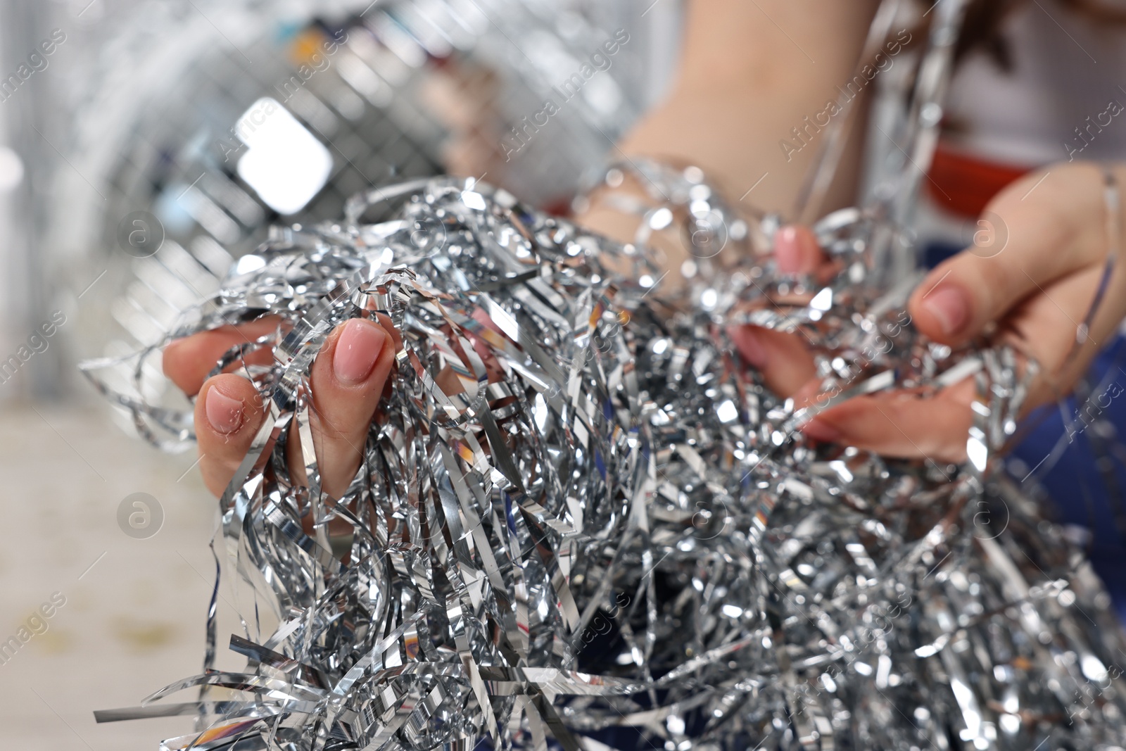 Photo of Woman with silver tinsel on floor indoors, closeup